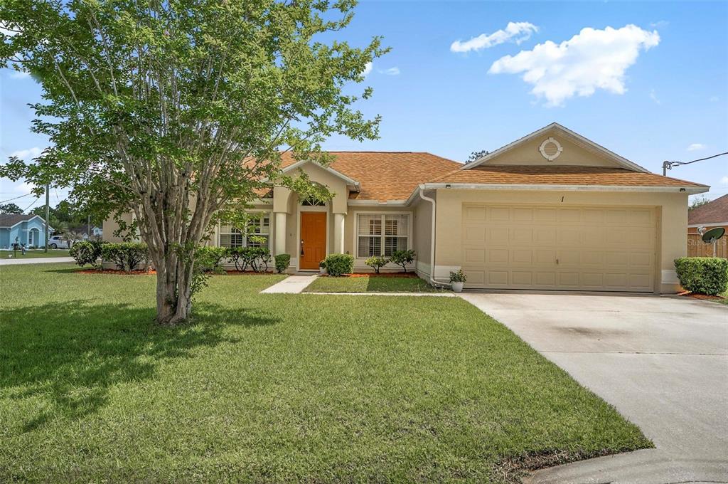 A single-story suburban house with a tan stucco exterior, orange front door, and two-car garage — 1 ETHAN PL, PALM COAST, FL