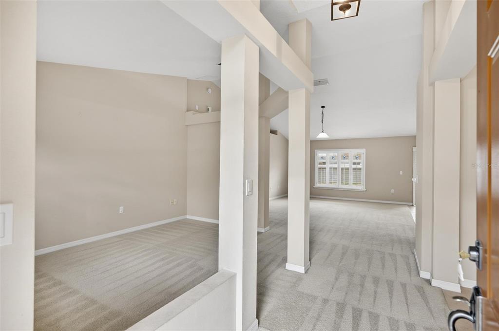 An interior view shows a carpeted living area with high ceilings and white support columns — 1 ETHAN PL, PALM COAST, FL