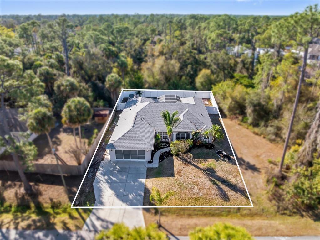 An aerial view shows a single-story house with a gray roof and a concrete driveway — 3707 GIBLIN DRIVE, NORTH PORT, FL