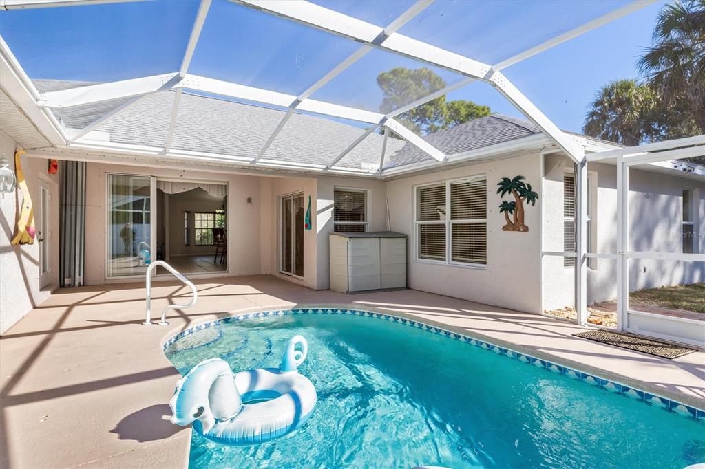 A screened-in patio features a swimming pool with a blue inflatable float — 3707 GIBLIN DRIVE, NORTH PORT, FL