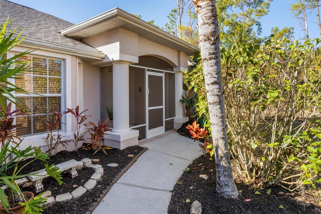 A concrete walkway leads to a screened-in entryway with white columns on a residential home — 3707 GIBLIN DRIVE, NORTH PORT, FL