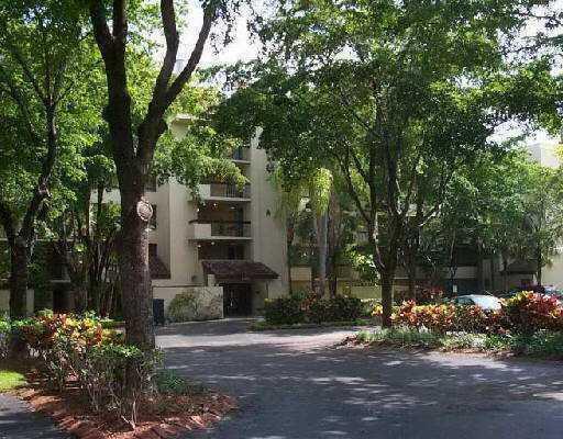 A multi-story apartment building is surrounded by lush trees and landscaped garden beds — 825 Egret Circle # 206, Delray Beach FL 33444, DELRAY BEACH, FL