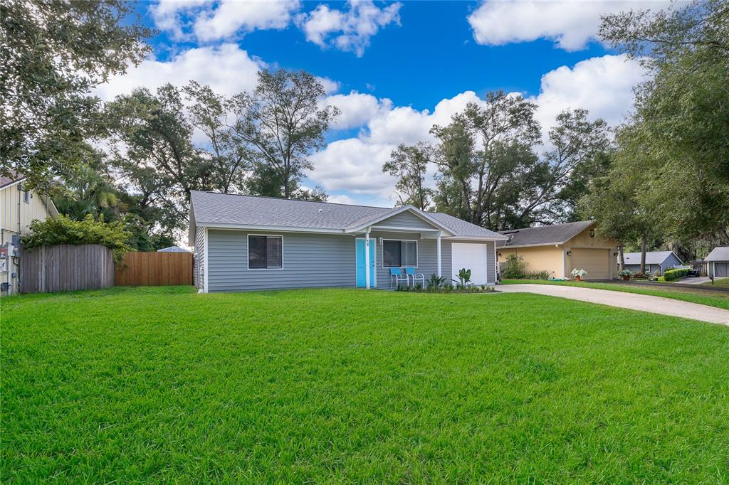 A single-story house with gray siding, a bright blue front door, and a grassy lawn — 15 N BULOVA DRIVE, APOPKA, FL
