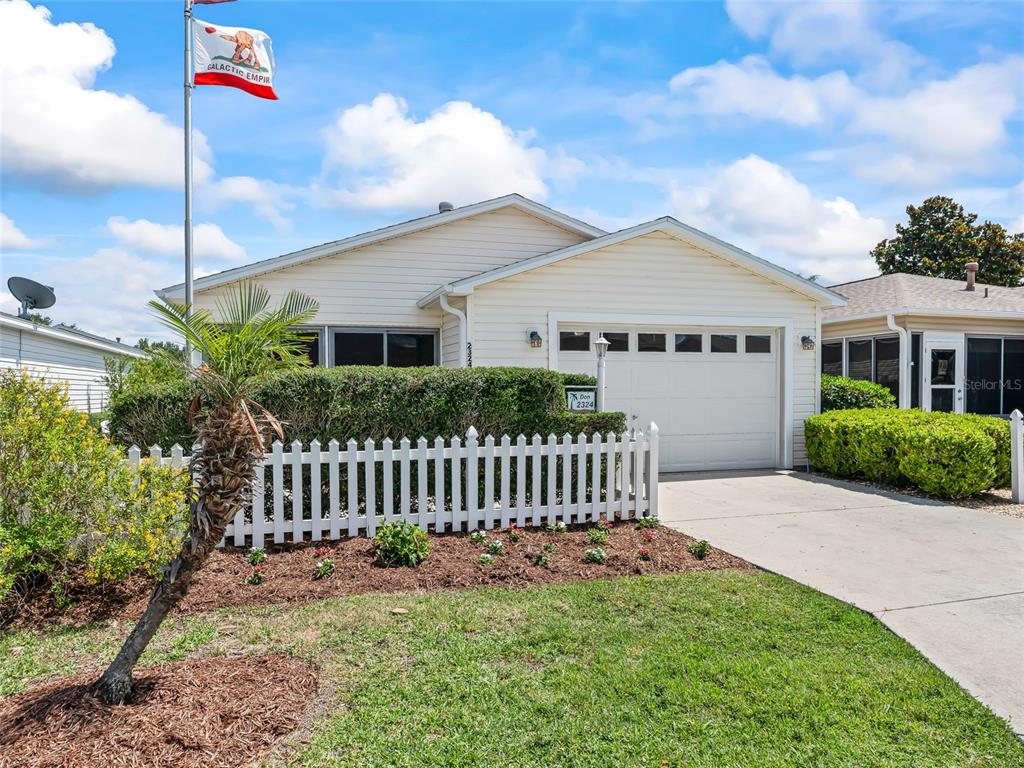 A single-story house with light siding, a white picket fence, and a flag pole — 2324 PICKENS PLACE, THE VILLAGES, FL
