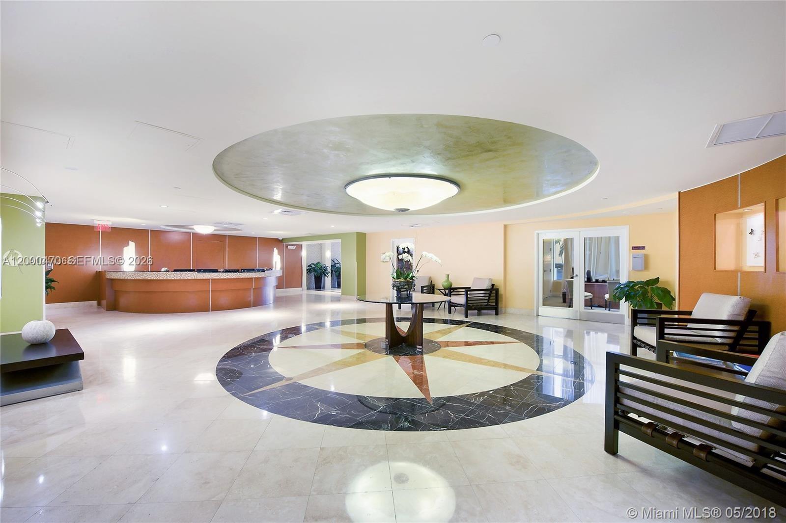 A spacious lobby features a circular ceiling light, a compass-patterned floor, and a reception desk — 7350 SW 89th St # 1707S, Miami FL 33156, MIAMI, FL