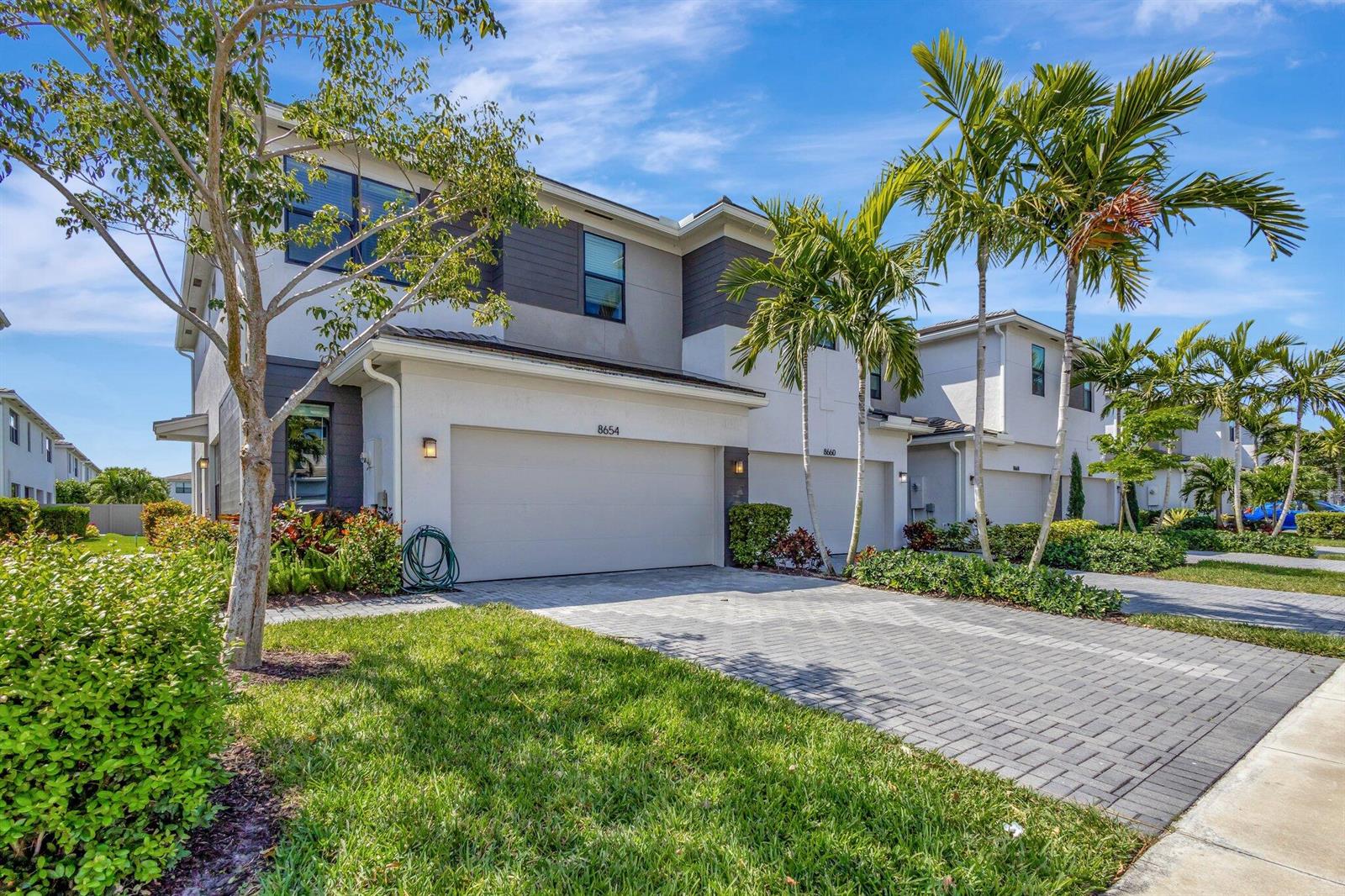 A two-story townhouse with a paved driveway, a two-car garage, and palm trees — 8654 Antarus Drive, Lake Worth FL 33467, LAKE WORTH, FL