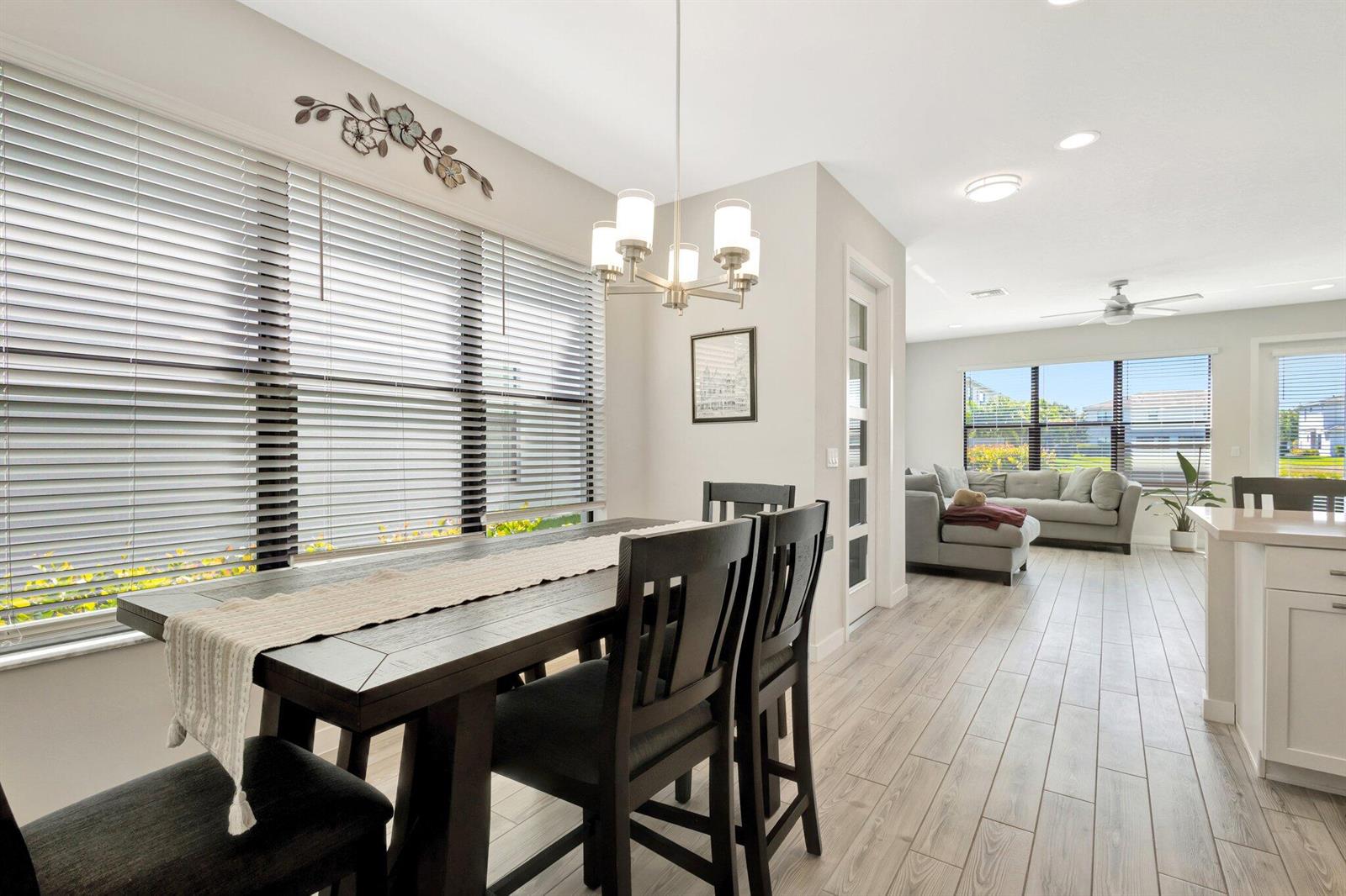 A dining area with a dark wood table and chairs sits beside a living room — 8654 Antarus Drive, Lake Worth FL 33467, LAKE WORTH, FL