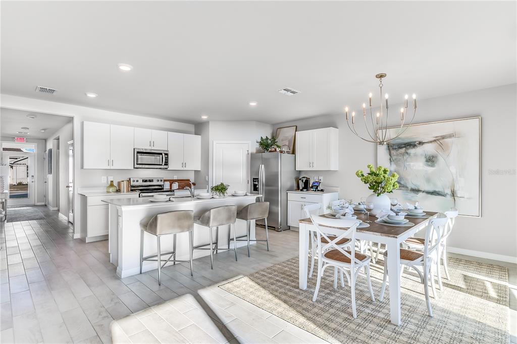 A modern kitchen and dining area feature white cabinetry, a center island, and tile flooring — 4924 TUSCOLA BOULEVARD, NORTH PORT, FL