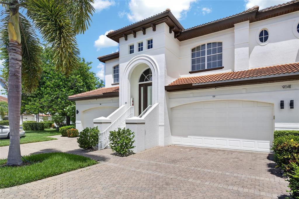 A two-story white stucco townhouse with a tile roof, arched entryway, and two garage doors — 9141 LOS LAGOS COURT UNIT 101, BONITA SPRINGS, FL