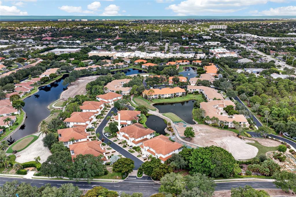 An aerial view shows a residential complex with multiple buildings, ponds, and landscaped grounds — 9141 LOS LAGOS COURT UNIT 101, BONITA SPRINGS, FL