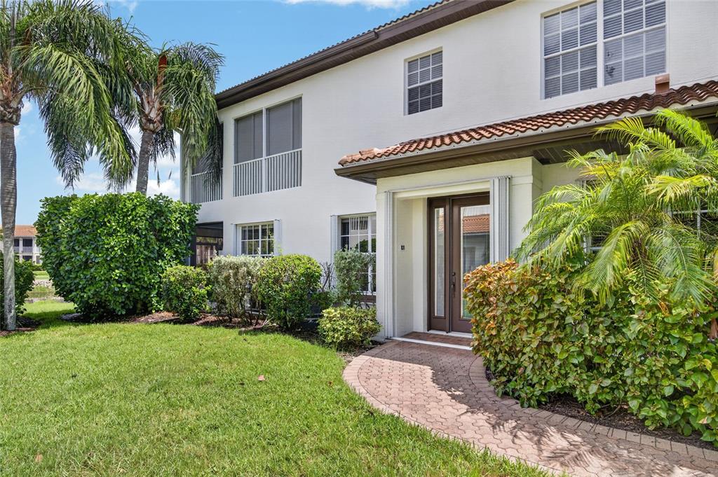 A two-story white stucco building with a tiled roof, palm trees, and a brick walkway — 9141 LOS LAGOS COURT UNIT 101, BONITA SPRINGS, FL