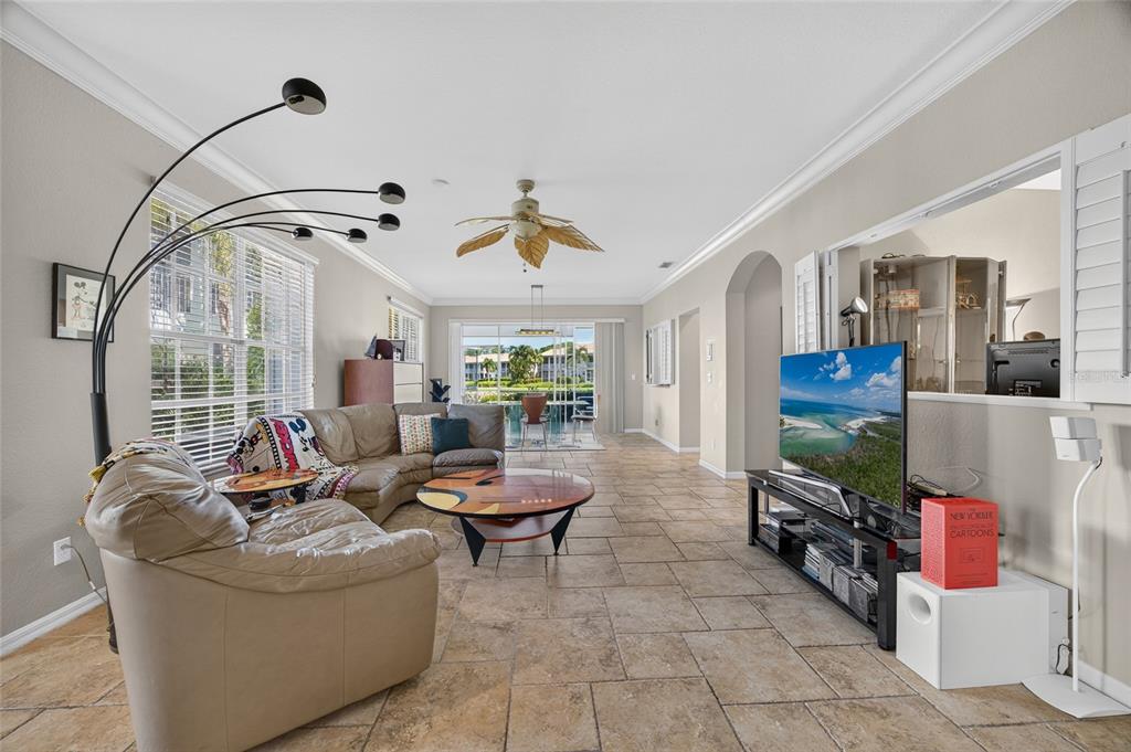 A living room features tile flooring, a sectional sofa, a television, and a ceiling fan — 9141 LOS LAGOS COURT UNIT 101, BONITA SPRINGS, FL