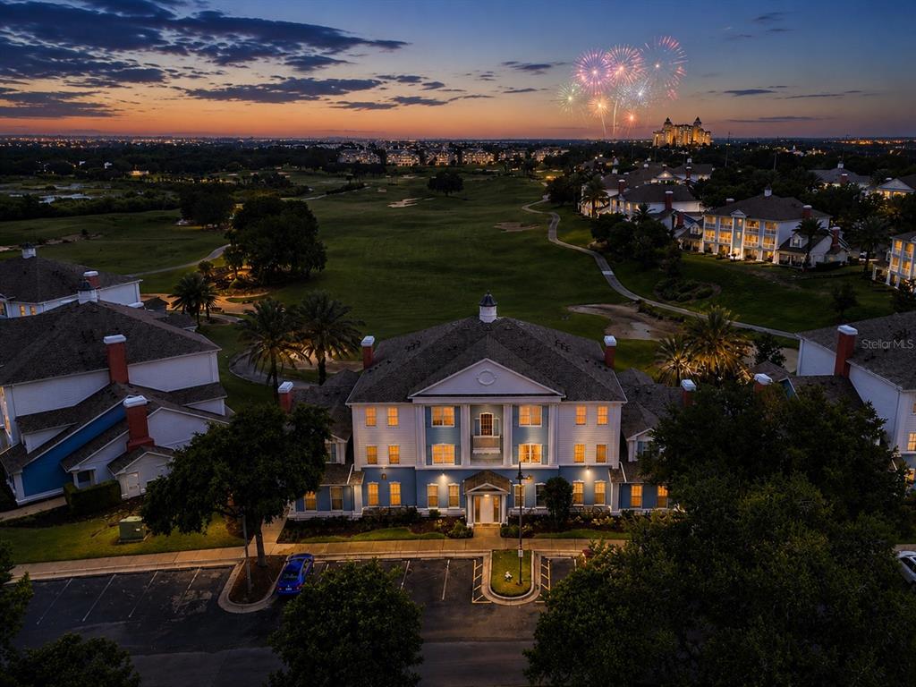 An aerial view of a multi-story building at dusk with fireworks visible in the distance — 7673 HERITAGE CROSSING WAY UNIT 102, REUNION, FL