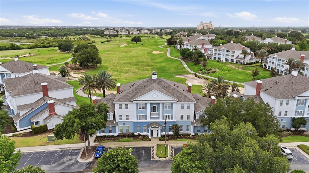 An aerial view shows multi-story apartment buildings situated along a green golf course — 7673 HERITAGE CROSSING WAY UNIT 102, REUNION, FL