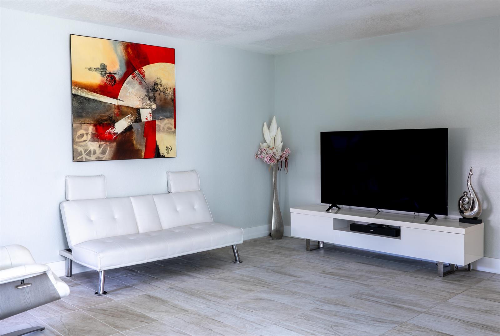 A living room features a white sofa, a television on a stand, and abstract wall art — 592 Fanshaw O, Boca Raton FL 33434, BOCA RATON, FL
