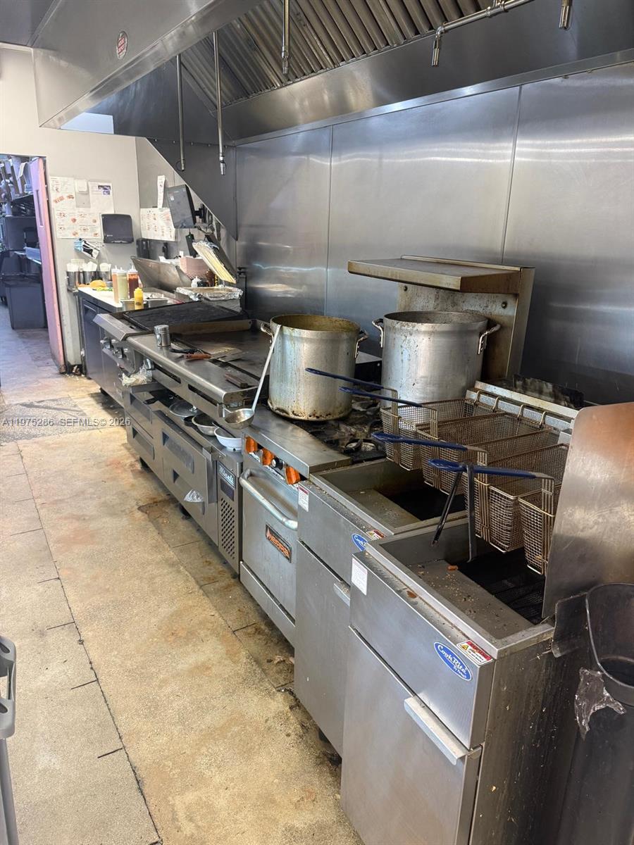 A commercial kitchen features stainless steel appliances, a large exhaust hood, and deep fryers — Confidential NW 67th Ave, Hialeah FL 33015, HIALEAH, FL