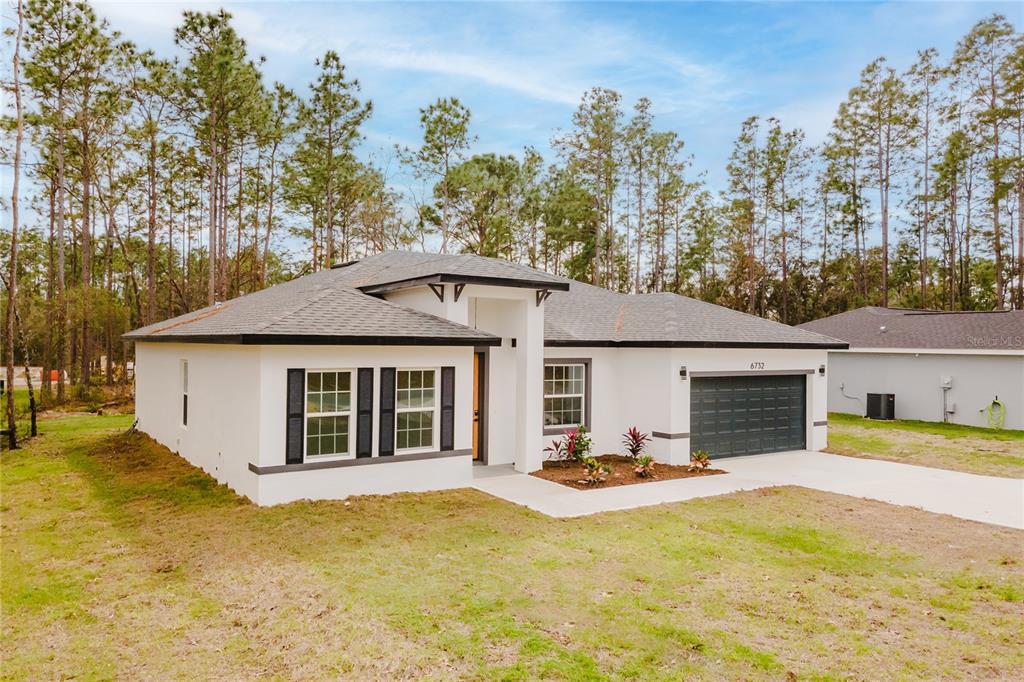 A single-story white house with a dark roof, black shutters, and a two-car garage — 6732 SW 132ND STREET, OCALA, FL