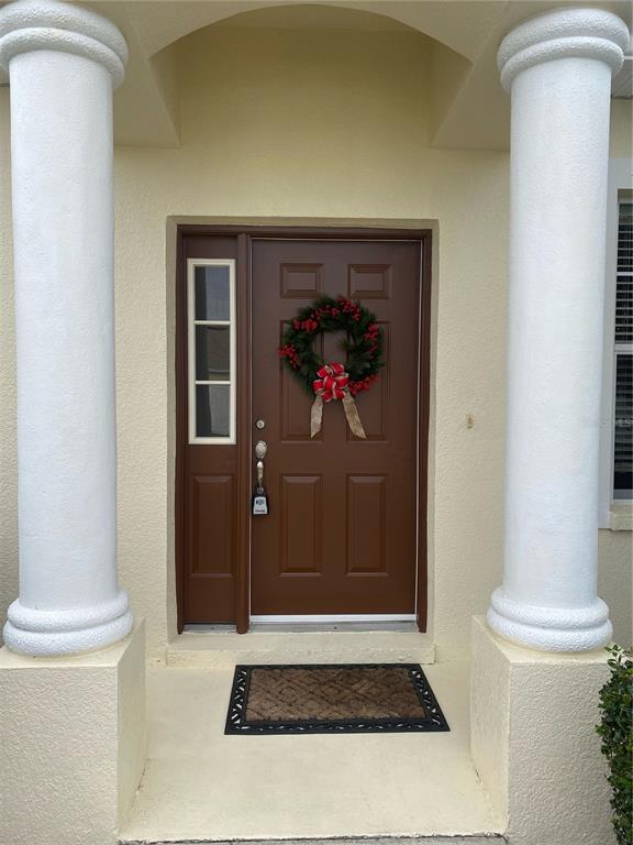 A brown front door with a wreath is framed by two white columns — 4711 MANDOLIN LOOP, WINTER HAVEN, FL