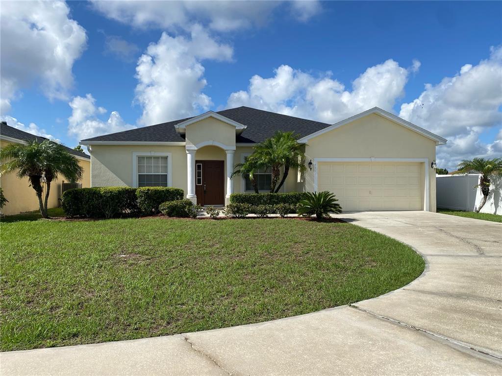 A single-story house with a yellow exterior, a two-car garage, and a curved driveway — 4711 MANDOLIN LOOP, WINTER HAVEN, FL