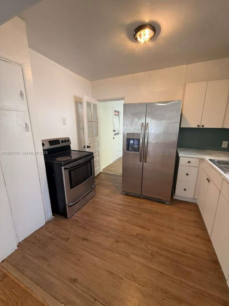 A kitchen features stainless steel appliances, white cabinets, and wood-look flooring — 300 NW 13th Ave, Miami FL 33125, MIAMI, FL