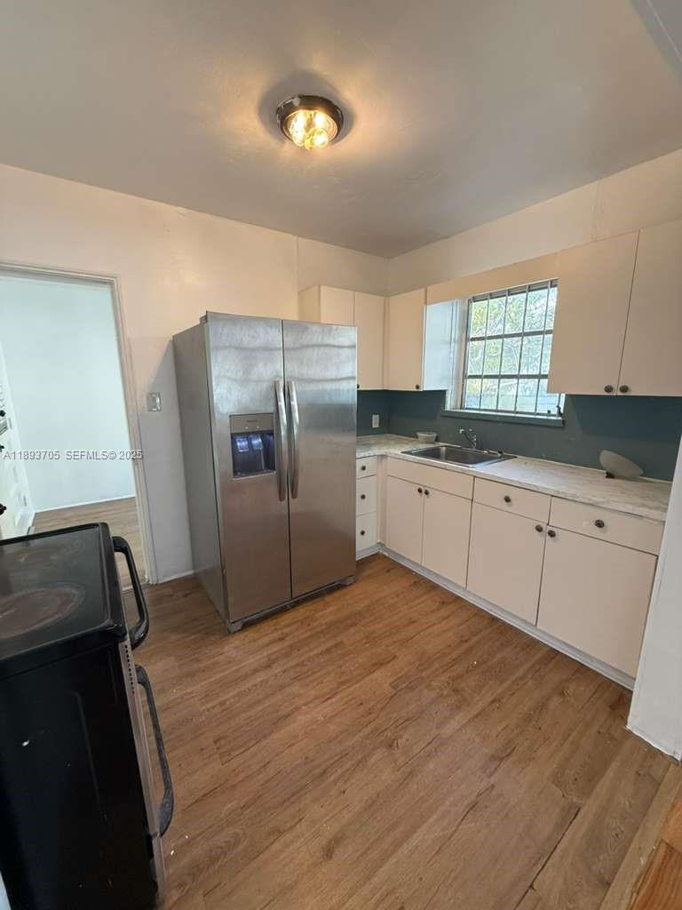 A kitchen features stainless steel appliances, light-colored cabinets, and wood-look flooring — 300 NW 13th Ave, Miami FL 33125, MIAMI, FL