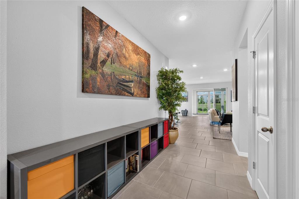A hallway with tiled floors, a long storage cubby unit, and a large landscape painting — 10675 TALLY FAWN LOOP, SAN ANTONIO, FL