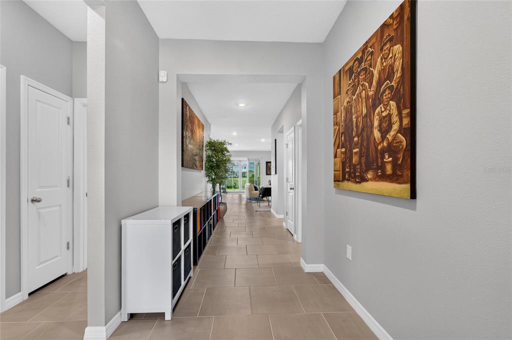 A hallway with tile flooring leads to a living area with a view of the outdoors — 10675 TALLY FAWN LOOP, SAN ANTONIO, FL