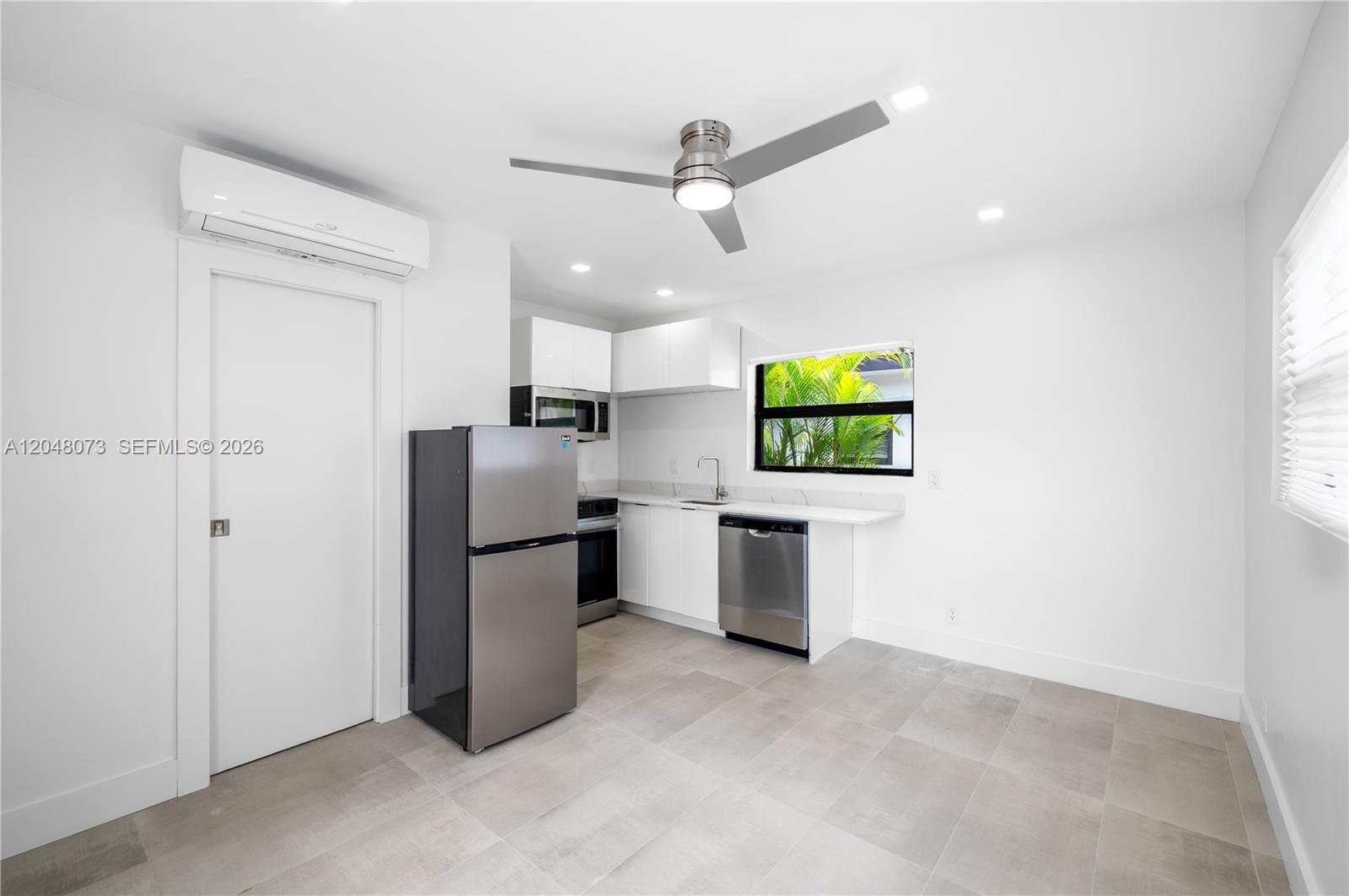 A modern kitchen features white cabinets, stainless steel appliances, and light gray tile flooring — 551 NE 26th St # 1, Wilton Manors FL 33305, WILTON MANORS, FL