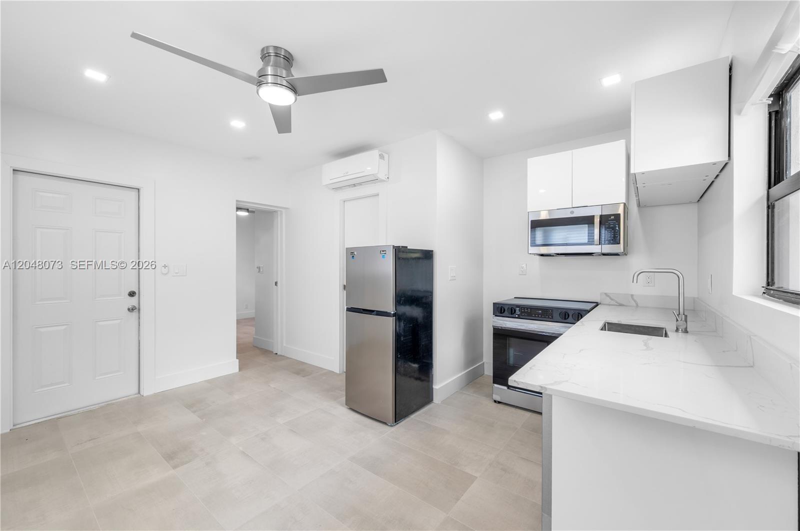 A modern kitchen features white cabinets, stainless steel appliances, and light-colored tile flooring — 551 NE 26th St # 1, Wilton Manors FL 33305, WILTON MANORS, FL