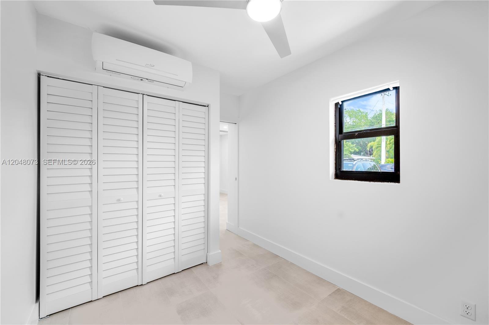 A bedroom features white walls, a louvered closet, a window, and a ceiling fan — 551 NE 26th St # 1, Wilton Manors FL 33305, WILTON MANORS, FL