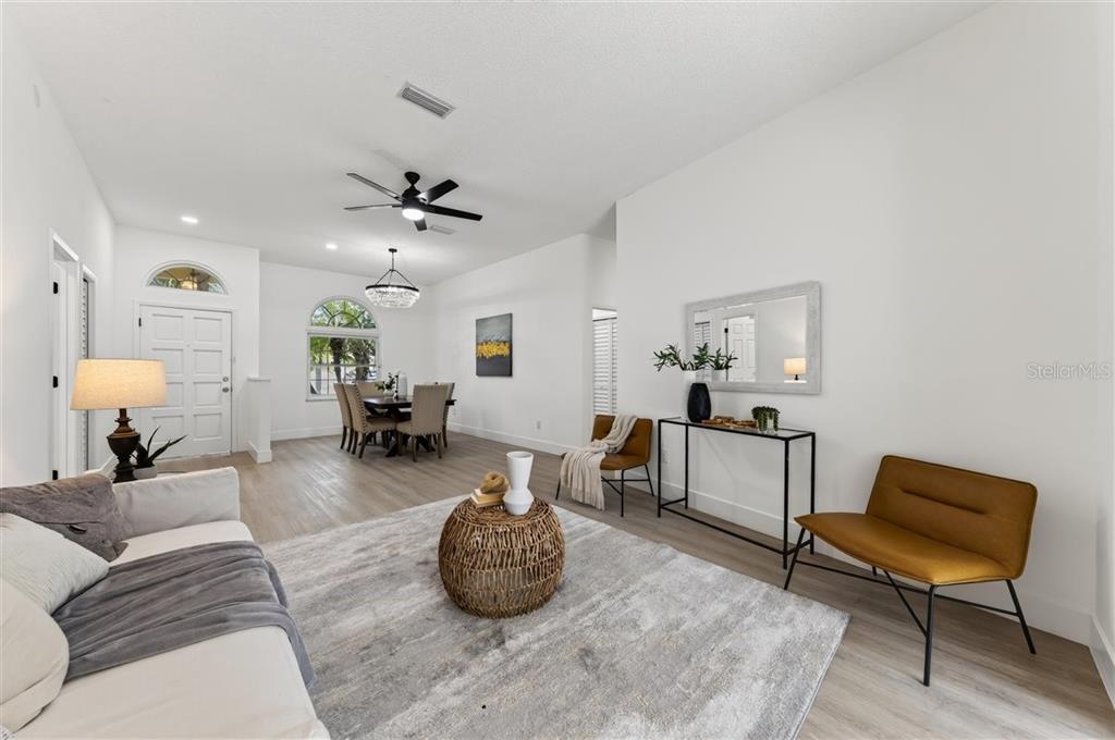 A bright living and dining area features white walls, light wood flooring, and modern furniture — 11318 POCKET BROOK DRIVE, TAMPA, FL