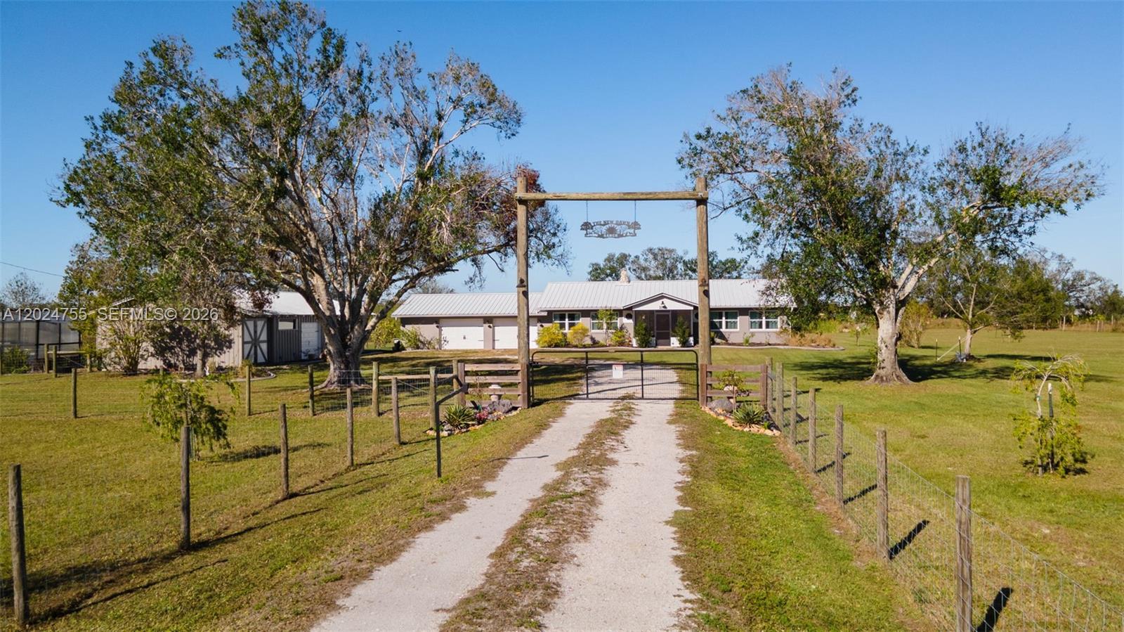 A gravel driveway leads through a gated entrance toward a single-story house with trees — OTHER CITY - IN THE STATE OF FLORIDA, FL