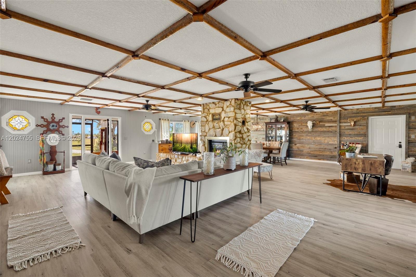 A spacious living room features a stone fireplace, wood-paneled walls, and a coffered ceiling — OTHER CITY - IN THE STATE OF FLORIDA, FL