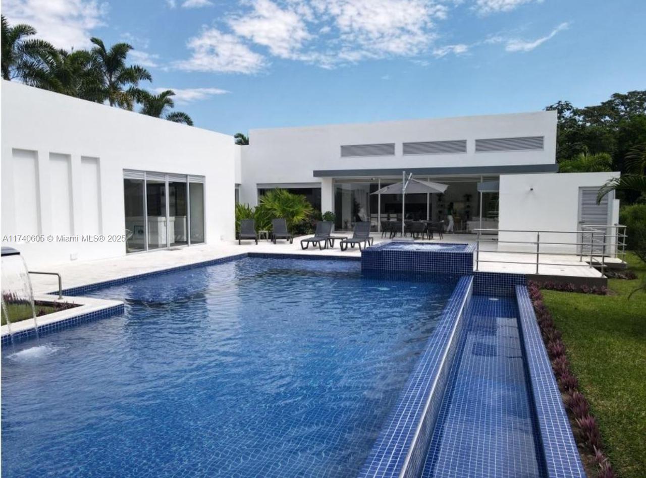 A modern white house features a large blue tiled swimming pool and patio area — OTHER COUNTRY - NOT IN USA, PP