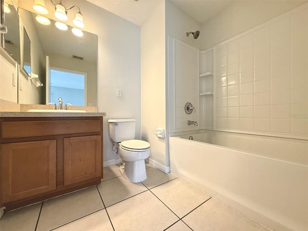 A bathroom features a wooden vanity, a white toilet, and a shower-tub combination with tiles — 2526 LEXINGTON OAK DRIVE, BRANDON, FL