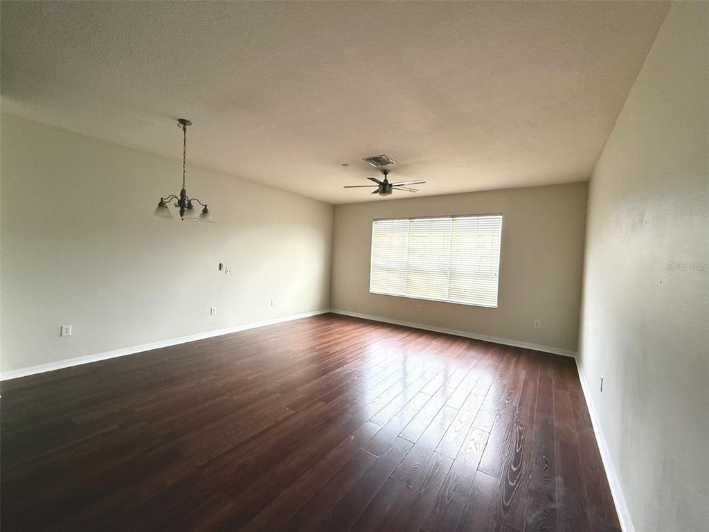 An empty room features dark wood flooring, a ceiling fan, and a hanging light fixture — 2526 LEXINGTON OAK DRIVE, BRANDON, FL