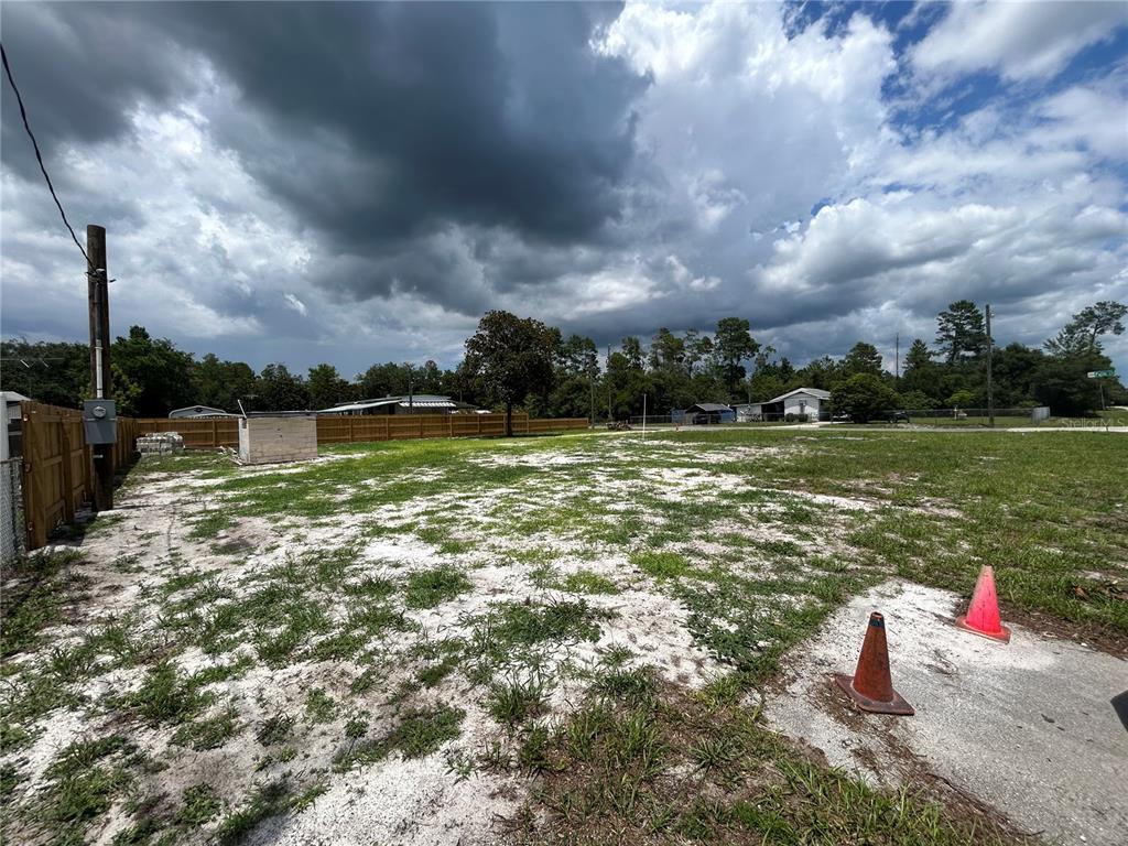 A vacant, grassy lot with a wooden fence, a small utility structure, and two traffic cones — 28245 BOUGAINVILLEA AVENUE, PAISLEY, FL