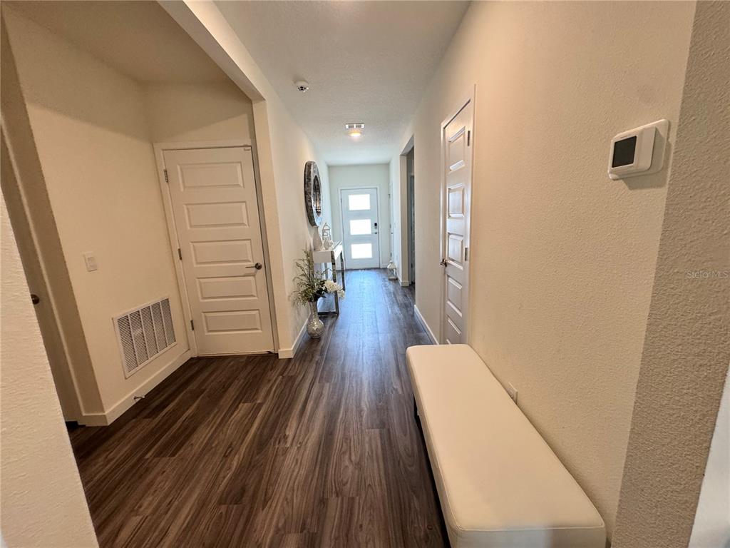 A hallway with wood-look flooring, a white bench, and a front door with glass panels — 415 TALISI LOOP, ST CLOUD, FL