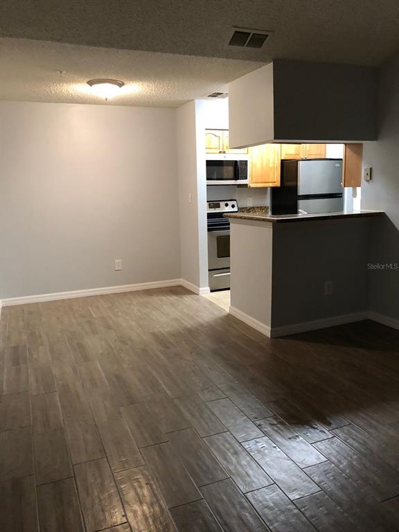 A dining area with wood-look tile flooring leads into a kitchen with a breakfast bar — 224 AFTON SQUARE UNIT 304, ALTAMONTE SPRINGS, FL