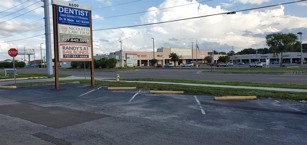 A commercial parking lot sits in front of a multi-tenant retail plaza and signage — 6609 RIDGE ROAD UNIT 2&4, PORT RICHEY, FL