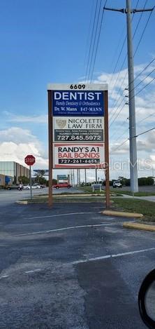A tall, multi-tenant business sign stands in a parking lot under a blue sky — 6609 RIDGE ROAD UNIT 2&4, PORT RICHEY, FL