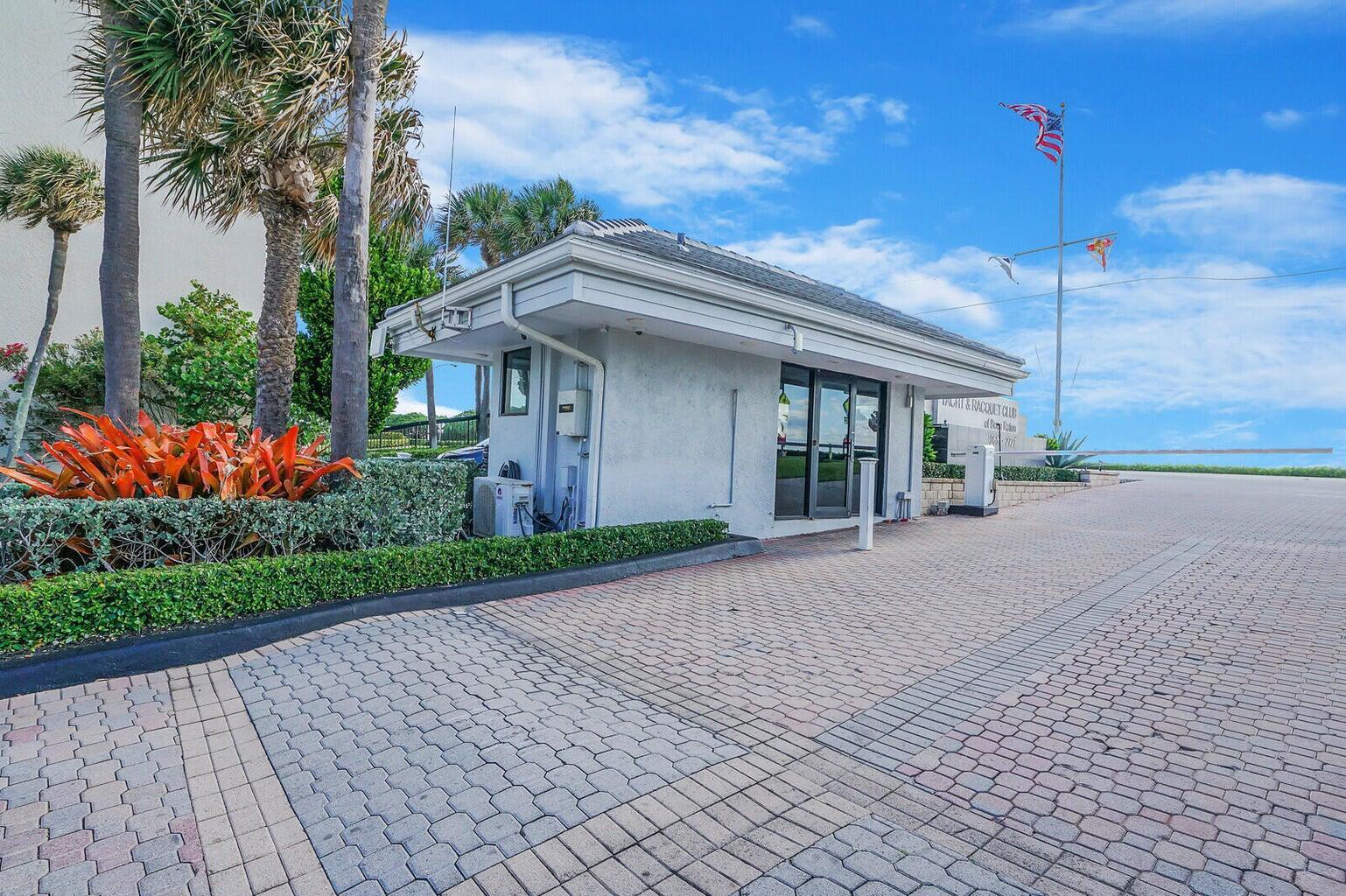 A gated entrance with a small guardhouse, paved driveway, and palm trees under a blue sky — 2687 N Ocean Boulevard # 305, Boca Raton FL 33431, BOCA RATON, FL