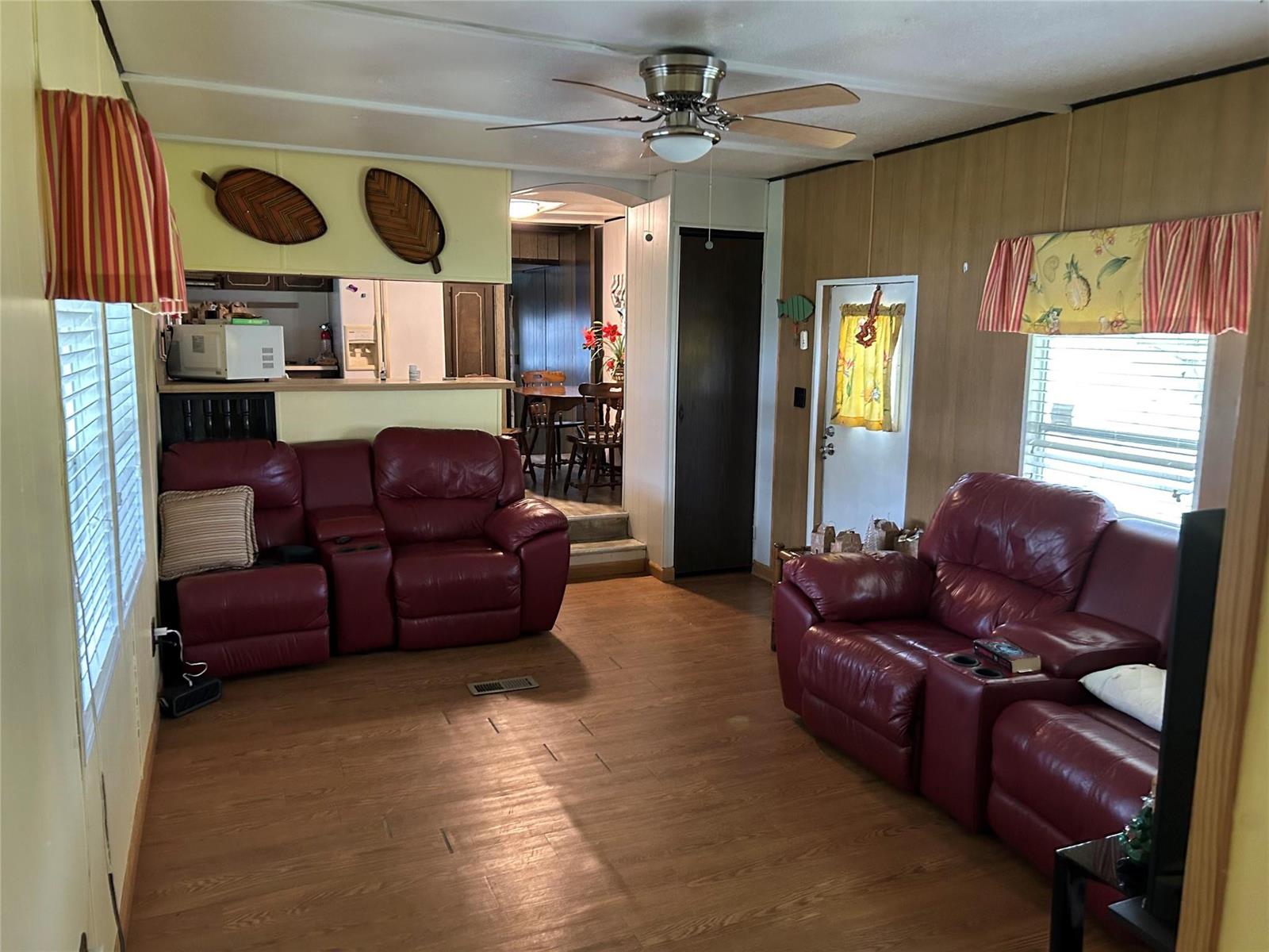 A living room features two red leather reclining sofas, wood-look flooring, and a ceiling fan — 1379 Chobee Street, Okeechobee FL 34974, OKEECHOBEE, FL