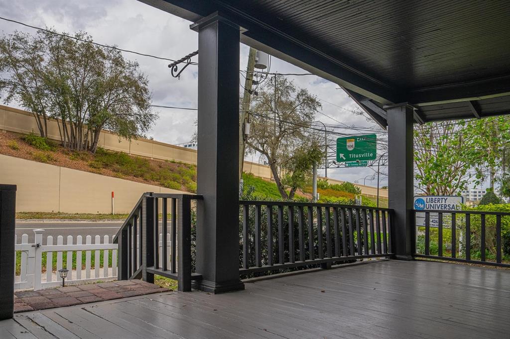 A dark-painted wooden porch with a railing overlooks a road and a highway overpass — 310 E ANDERSON STREET, ORLANDO, FL