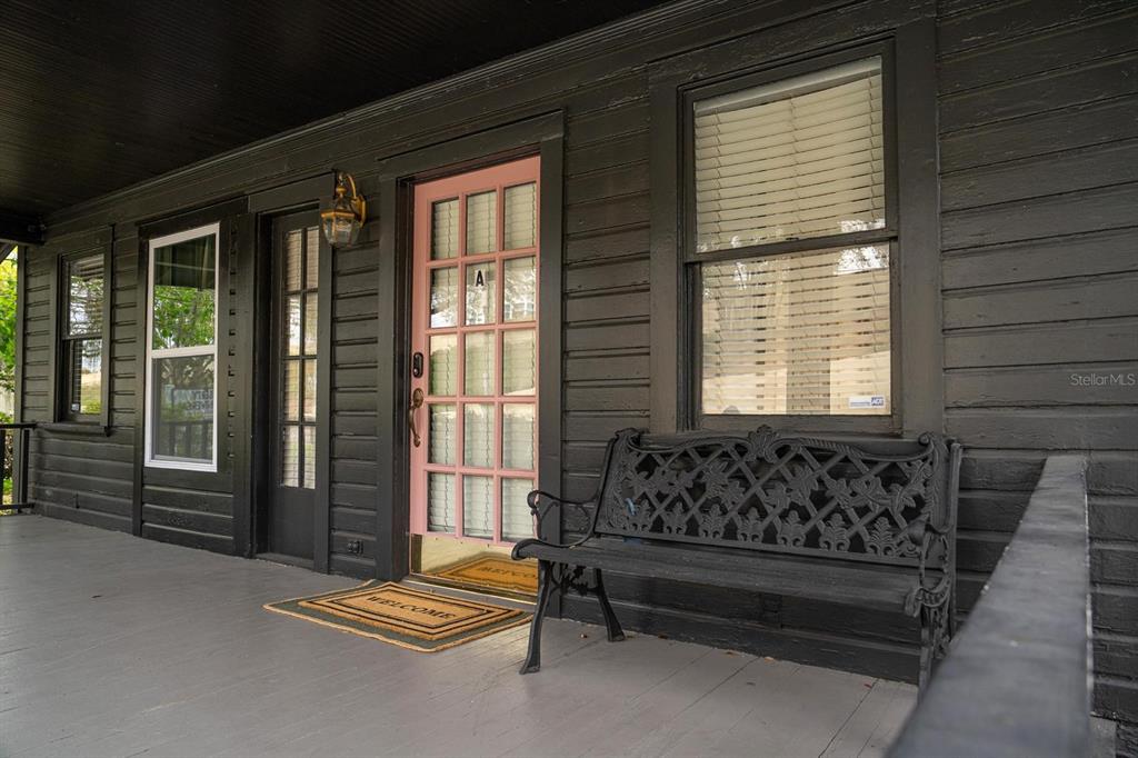 A black-painted porch features a pink front door, a metal bench, and two windows — 310 E ANDERSON STREET, ORLANDO, FL