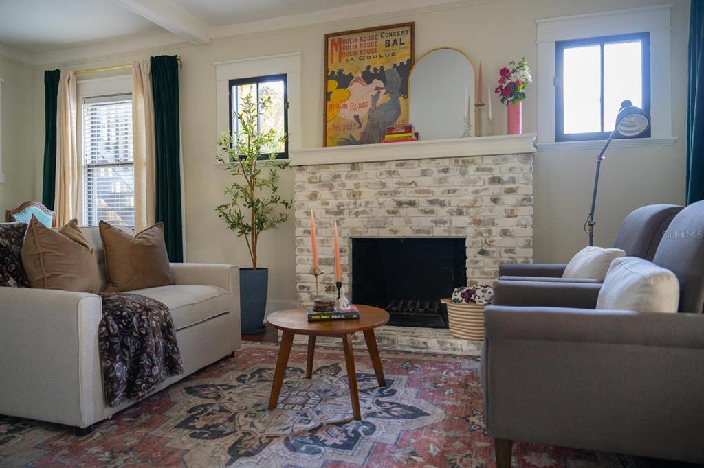 A living room features a whitewashed brick fireplace, a patterned rug, and two armchairs — 310 E ANDERSON STREET, ORLANDO, FL