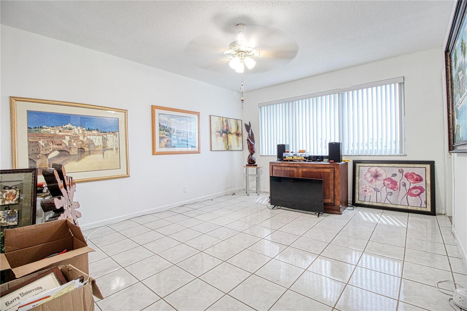 A living room with white walls, tiled floors, a ceiling fan, and several framed artworks — 2300 Park Lane # 311, Hollywood FL 33021, HOLLYWOOD, FL