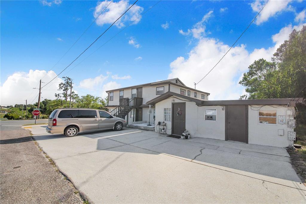 A two-story building with a concrete driveway, a parked minivan, and an attached garage — 402 E MAIN STREET, DUNDEE, FL