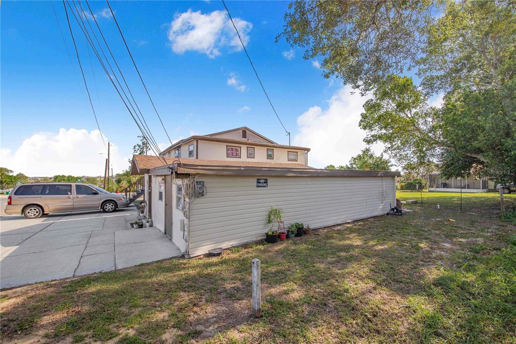 A beige, single-story detached garage sits next to a multi-story house and a parked van — 402 E MAIN STREET, DUNDEE, FL