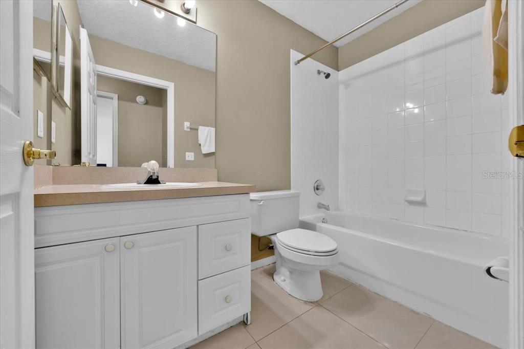 A bathroom features a white vanity, a toilet, and a shower-tub combination with white tiles — 352 CARIBBEAN DRIVE UNIT Front, DAVENPORT, FL